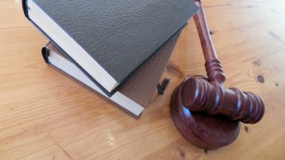 a wooden gavel laying on a table next to a stack of books, meant to represent the article "4 bizarre case rulings" by MMRBH Law Office.