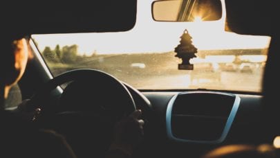 A photo taken from the backseat of a car, showcasing a new teen driver in the front seat. Parents should be wary of teen driver car accident prevention before handing over the keys.