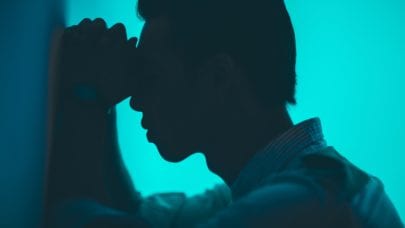 A person leaning against the wall in what appears to be pain and suffering.