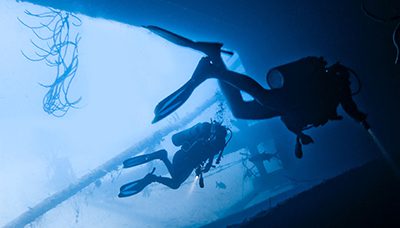 Two commercial scuba divers explore underwater. This photo serves as a header image for the article "The Role of Negligence in Commercial Diving Accidents" by MMRBH Law Office.