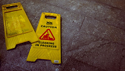 Two wet floor signs laying on the ground, meant to represent the article "What to Do if You Slip and Fall at Work" by MMRBH Law Office.