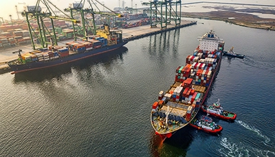 Two large cargo ships in the process of docking at a ship yard. This photo is meant to serve as a header image for the blog "5 facts about maintenance and cure benefits" by MMRBH Law Firm.